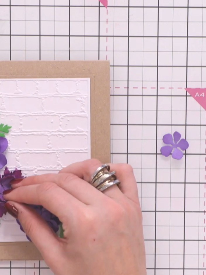 Step 12: Arrange and glue your largest purple flower to the left side of the card. Layer the smaller dark pink and purp