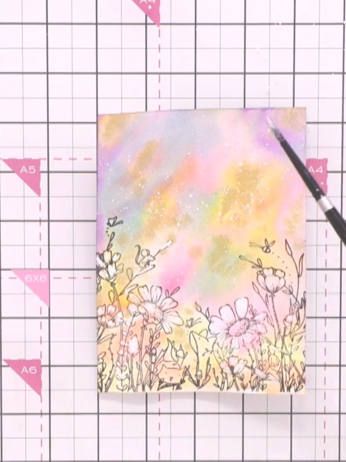 Step 10: Add white detail to the top of the card by tapping a brush loaded with white paint or ink to create a dreamy, 
