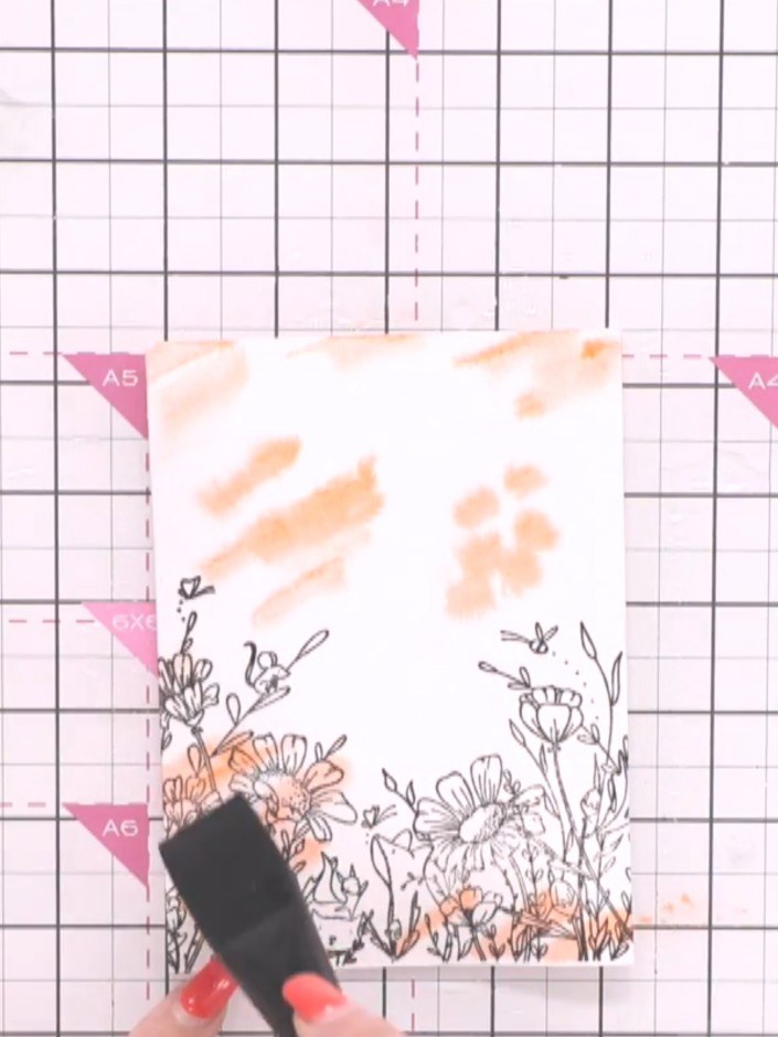 Step 3: Drop orange watercolour paint onto the wet paper, spotting it randomly across the surface. Use a blending brus
