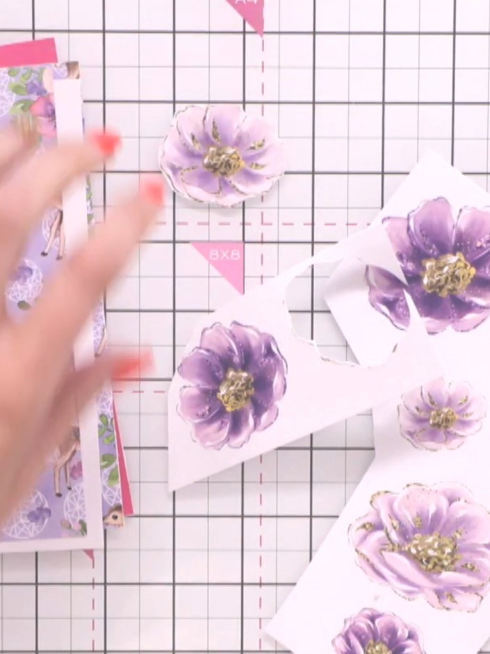 Step 2: Carefully cut around two to three purple flowers from the patterned paper using scissors. Work slowly around t