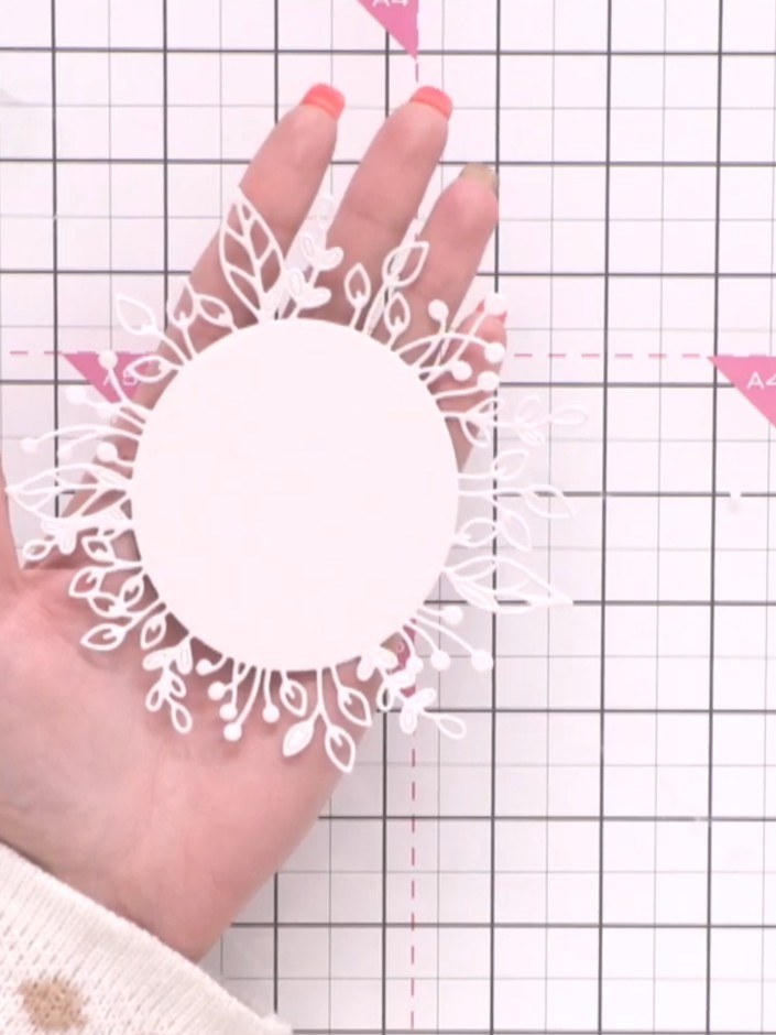 Step 1: Cut several wreath die shapes from white cardstock. Position a grey card base on your craft mat to begin build