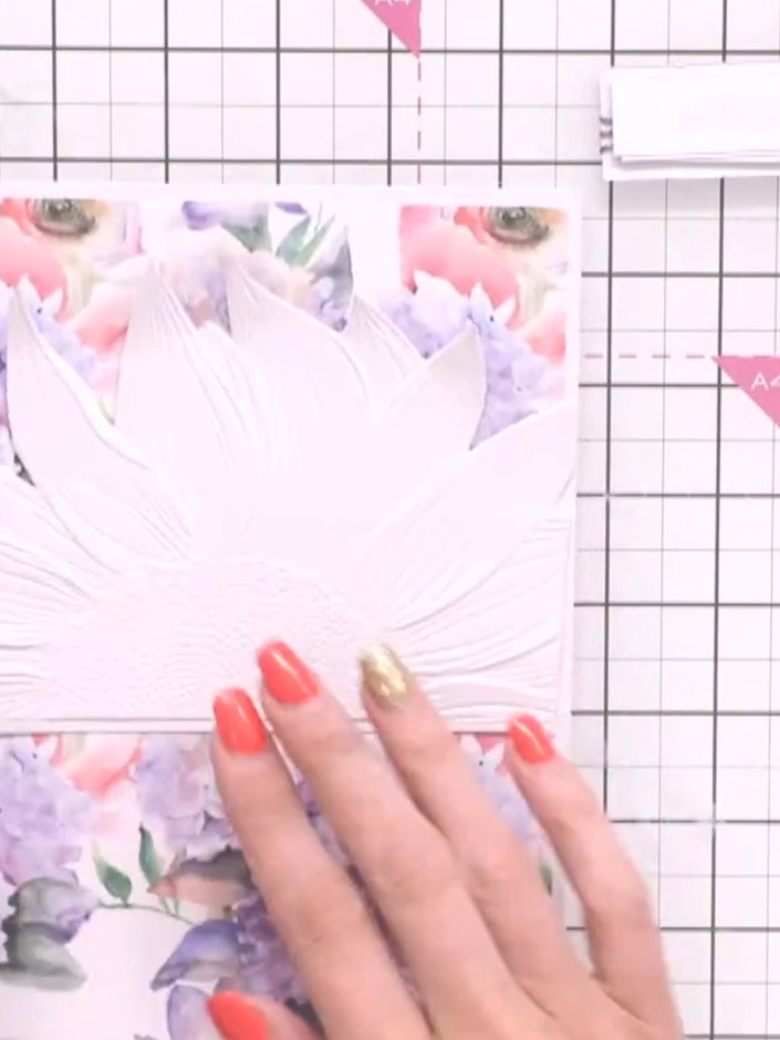 Step 10: Position the white embossed sunflower panel centrally on the floral patterned card front and adhere it in plac