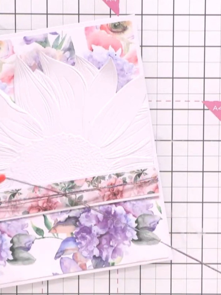 Step 11: Create a bow from the decorative wrap or ribbon. Attach the bow to the side of the card near the floral design