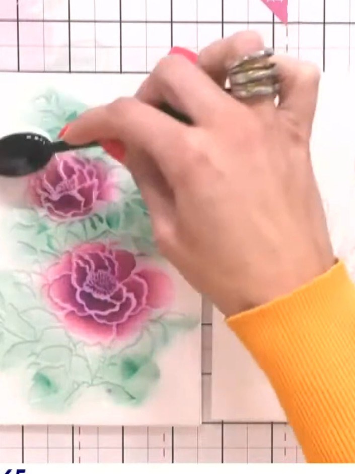 Step 4: Trag grüne Stempelfarbe durch die Schablone auf, um Blattwerk zu ergänzen und die Farbpalette rund um die rosa Blüten aufzubauen.
