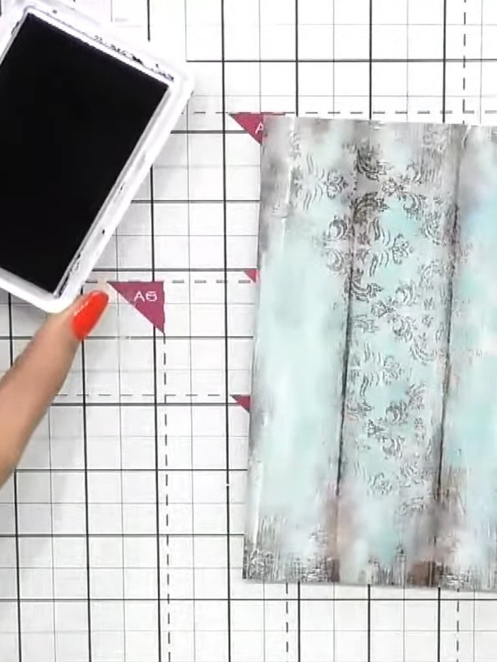 Step 1: Cut a piece of textured paper from the Wistful Charm paper pad. Use blue and purple ink pads to swatch colour 
