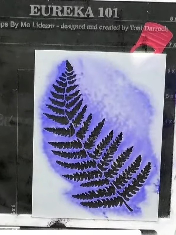 Step 7: Position the fern stencil slightly offset from its original position on the card. Tap white ink through the st