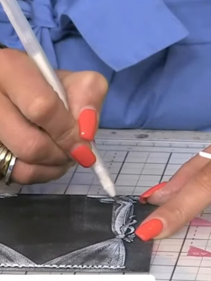 Step 7: Mount the embossed and inked curtain panel onto a black card blank. Use a white pen to add highlights and deta