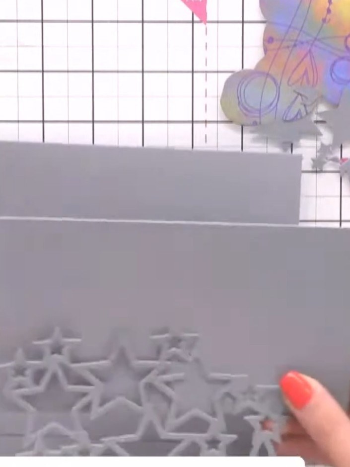 Step 5: Glue the grey patterned paper piece with the cut-out stars to the front of your card base, aligning it careful