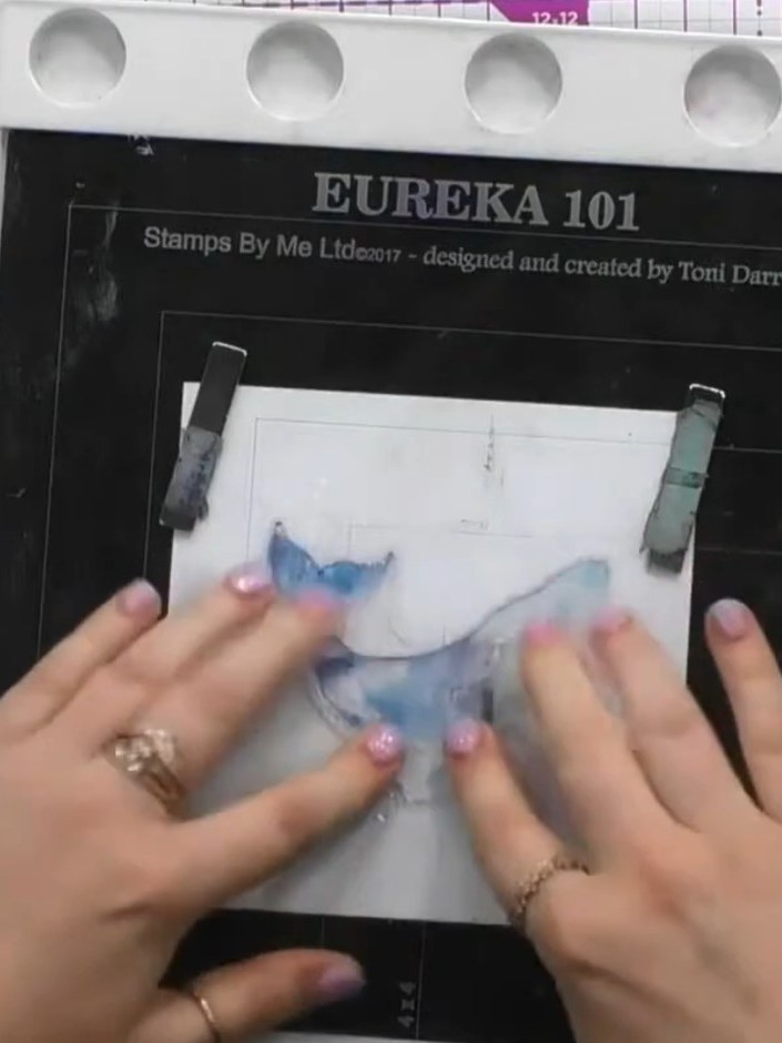 Step 3: Spritz water onto the stamped whale images using a water spray bottle. Allow the water to react with the ink f