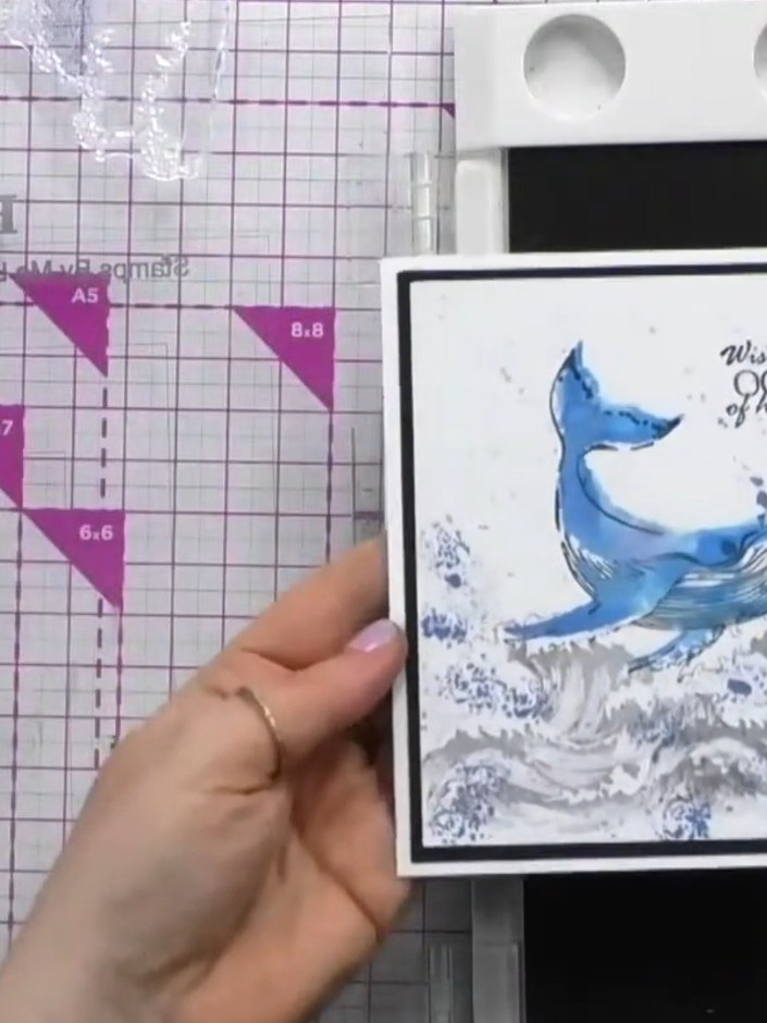 Step 8: Mount your finished watercolour whale image onto a black card base. Add the sentiment stamp 'Wishing you OCEAN