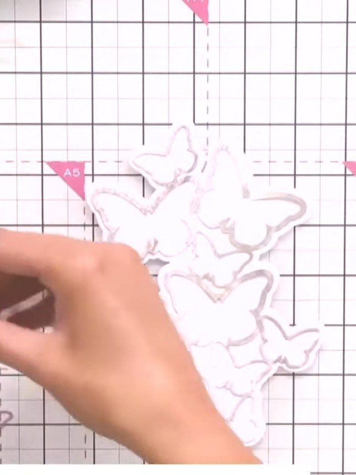 Step 3: Adhere the patterned paper butterfly background panel onto a white card base using tape or glue. Ensure the pa