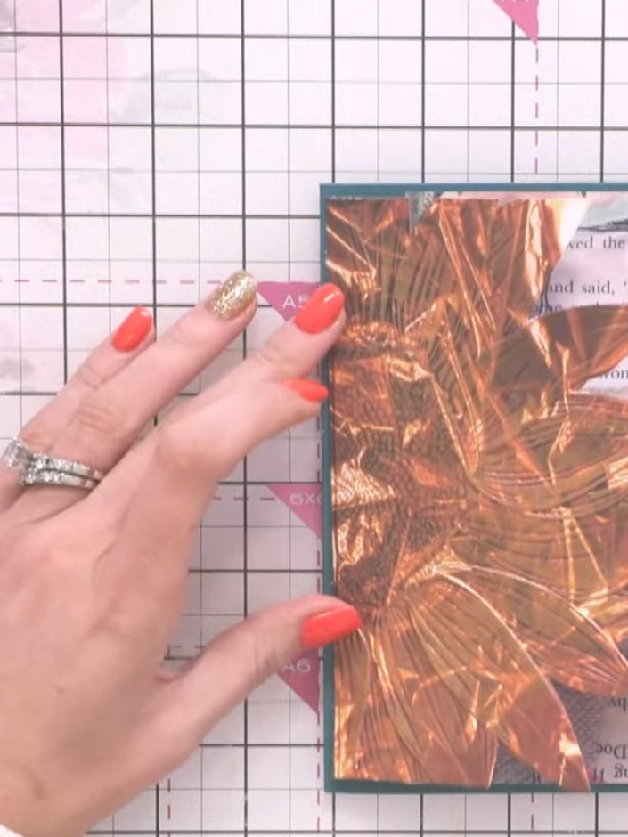 Step 7: Adhere the collage paper layer with the copper foil to the side of the teal card base. Pinch the edges slightl