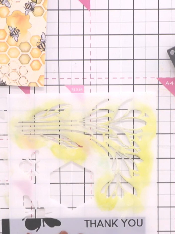 Step 9: Position a 'thank you' stencil onto the strip of black card stock. Using a blending sponge, apply yellow ink t