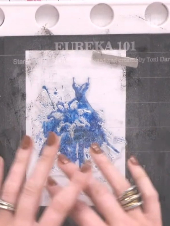 Step 3: Use a heat tool to completely dry the watercoloured card. Hold the heat tool over the blue dress design until 