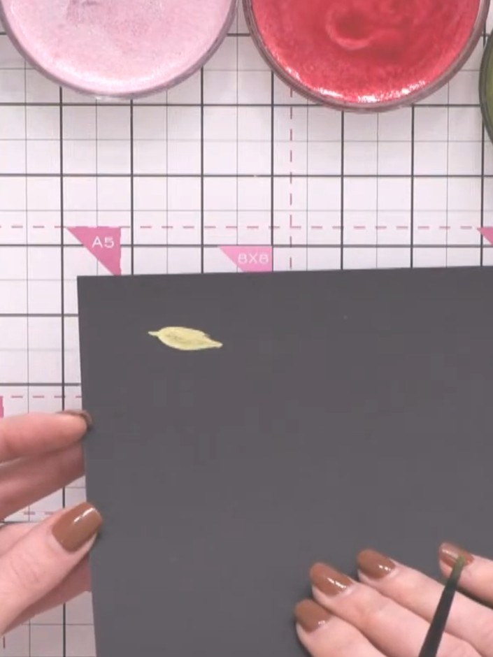 Step 4: Using the green metallic confetti ink, paint leaf shapes between the gold leaves. Rotate the card as you work 