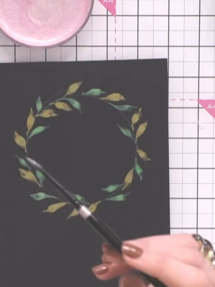 Step 6: Mix pink or red confetti ink and use a brush to add berry clusters in groups of three around the wreath. Place