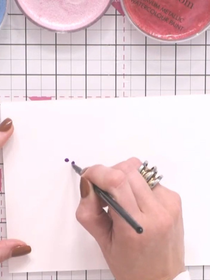 Step 2: Wet your brush thoroughly with clean water. Touch the wet brush to the wet purple paint on the paper, allowing