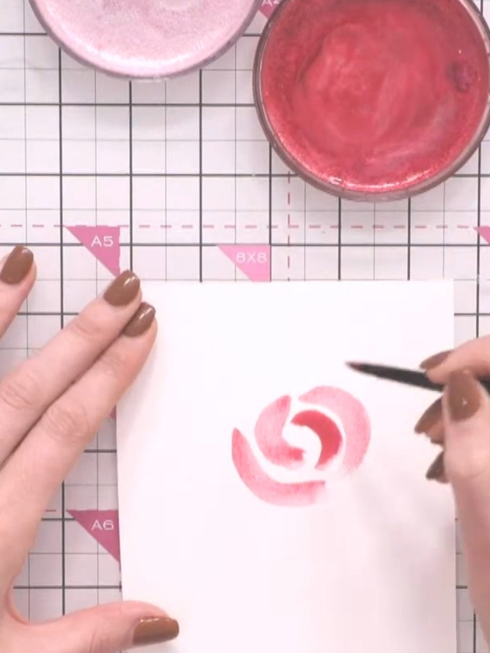 Step 5: Using a brush with pink ink, paint a series of curved C-shapes in the centre of your card to suggest rose peta