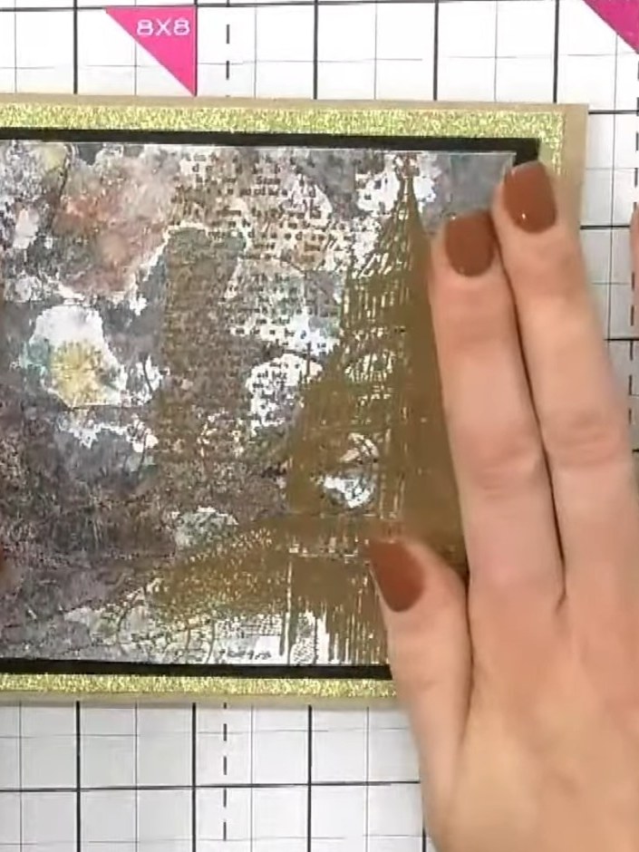 Step 4: Apply adhesive to the back of the stamped panel and mount it onto the gold glitter-framed black card blank, en