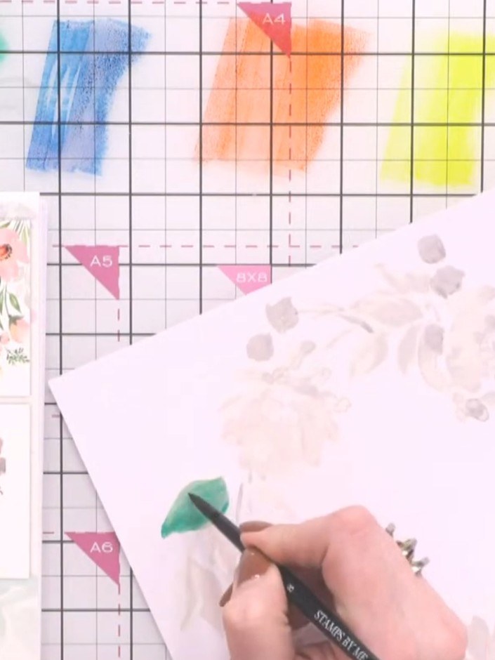 Step 4: Using green watercolour, paint the leaves and stems of the wreath, following the grey-scale guide underneath. 