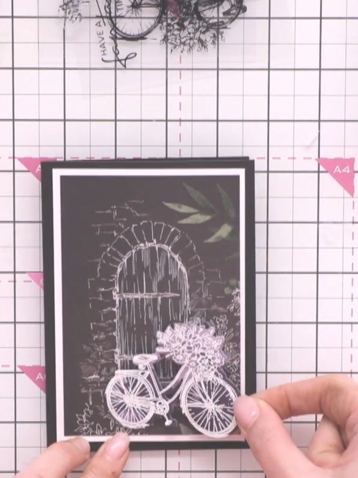 Step 11: Position the gold embossed die-cut bicycle onto the card front, angling the front wheel down slightly for pers
