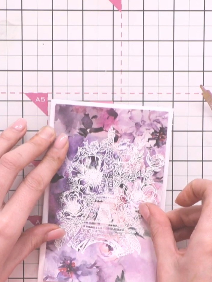 Step 10: Layer the gold-embossed Eiffel Tower on top of the white-embossed tower piece, creating a two-tone effect. Pos
