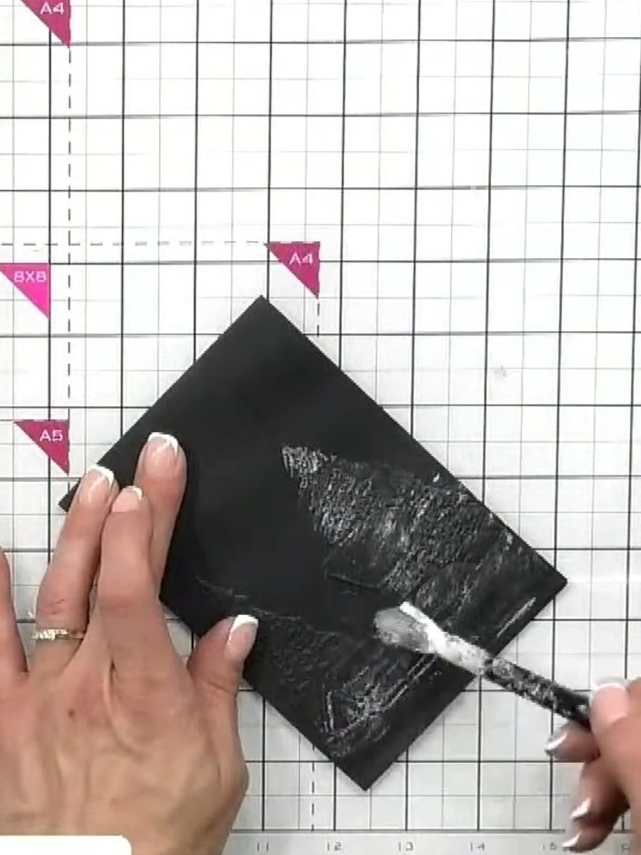 Step 4: Apply white acrylic texture paste lightly over the embossed black card using a dry brush technique. Work with 