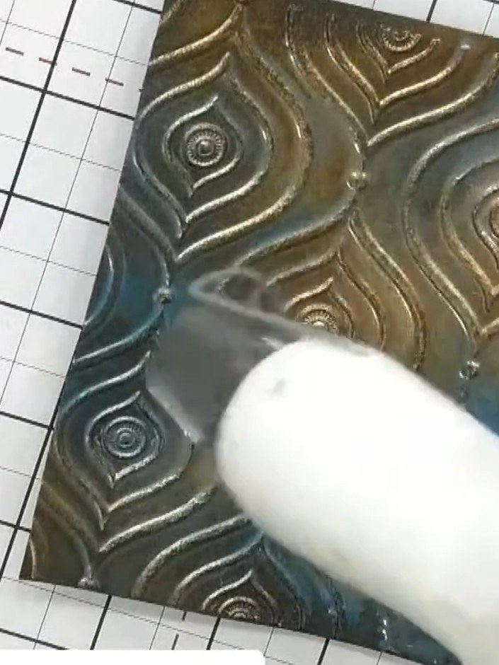 Step 6: Use a brayer with black ink to roll over the embossed and sprayed design. This will add definition and pull ou
