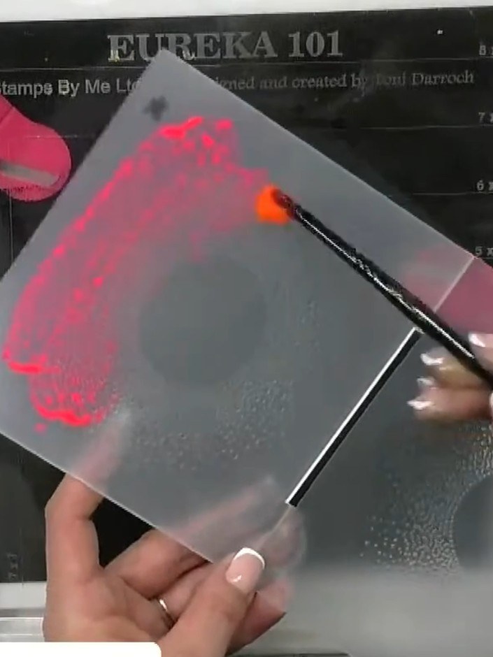 Step 2: Apply neon orange watercolour paint to one section of the embossing folder's raised areas using a brush. Work 