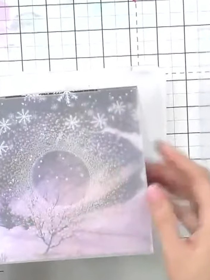 Step 1: Select a piece of patterned paper featuring a winter scene with trees and snowflakes in purple, pink and grey 