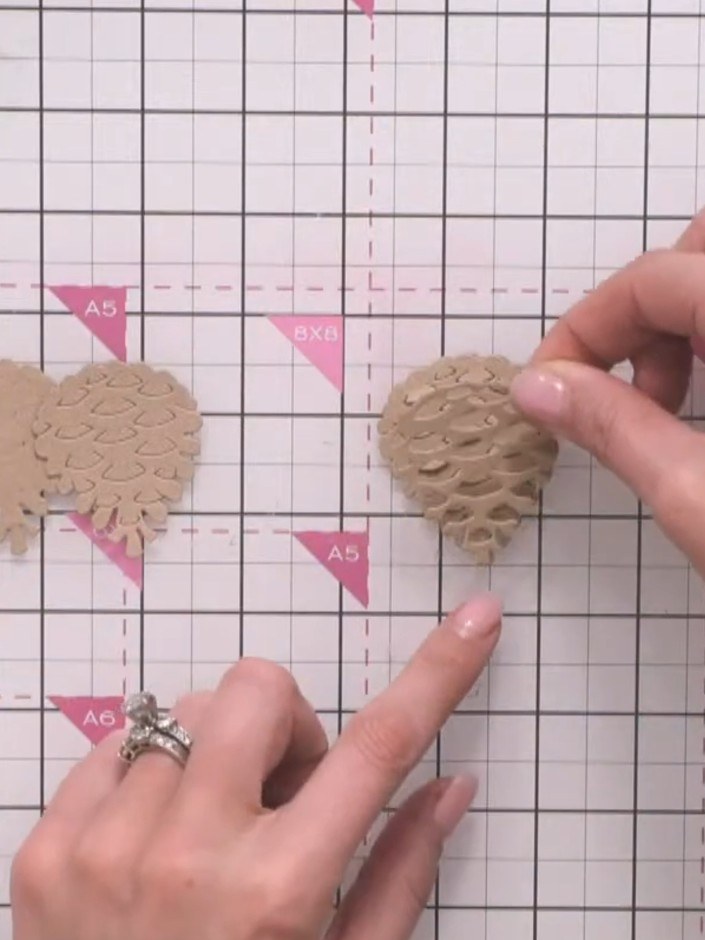 Step 8: Apply glue to the back of the second textured pine cone layer, being careful to avoid the lifted scale flaps t