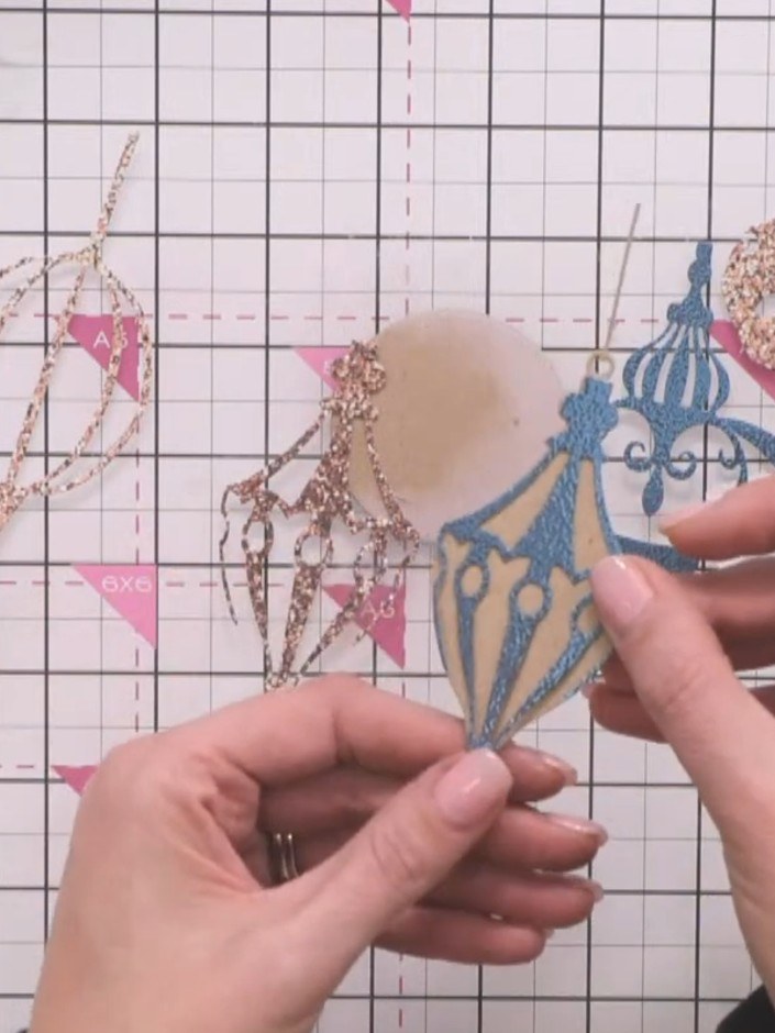 Step 7: Layer the teal decorative bauble die-cut piece over the inked kraft bauble base. Align the pieces carefully to