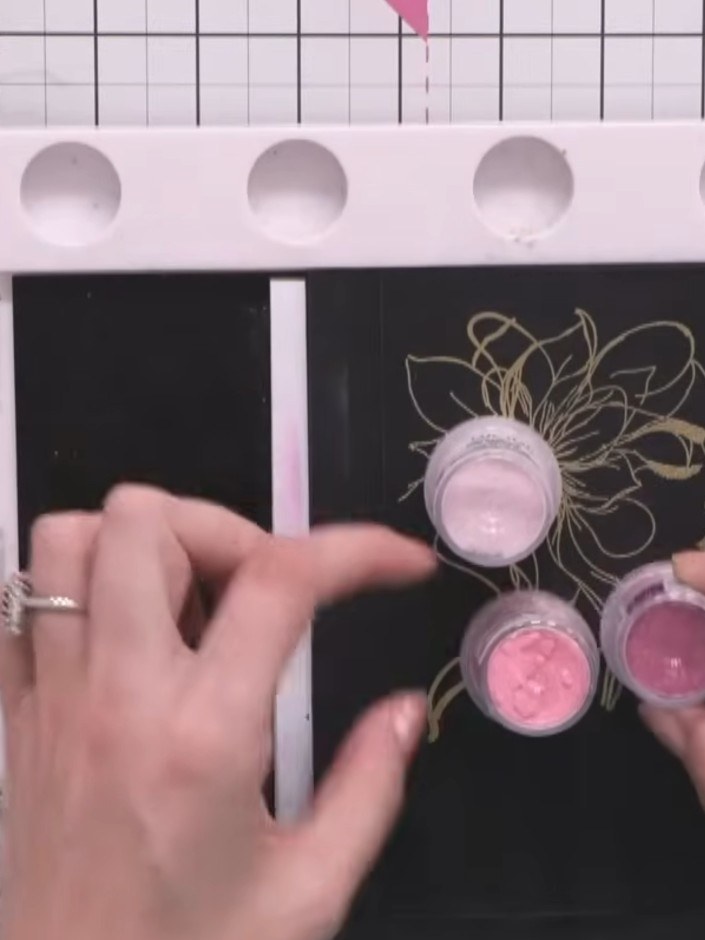 Step 5: Re-ink the stamped image on the card with the sticky embossing pad. Apply the lighter pink embossing powder fr