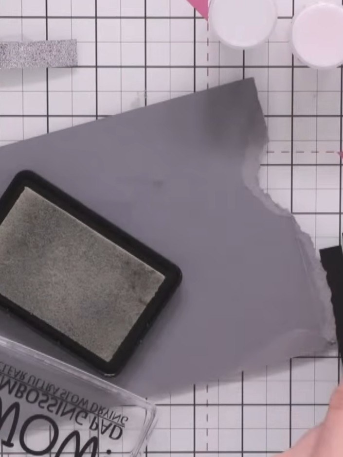 Step 3: Use a heat gun to heat set the embossing powder on the first grey strip until the powder melts and becomes glo