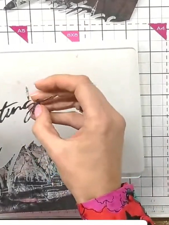 Step 3: Carefully remove the top die-cut 'Greetings' word piece from the painted mount and set it aside for later use.