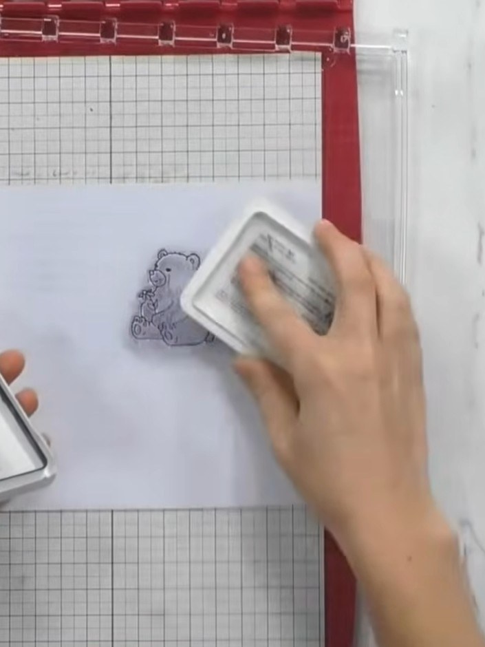 Step 1: Stamp a forest animal design onto white card using the stencil and stamp tool with pink ink. Press the stamp f