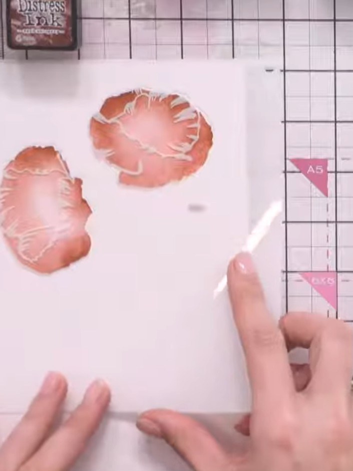 Step 4: Position the second poppy stencil over your card and apply orange Distress Ink through the stencil. Press firm