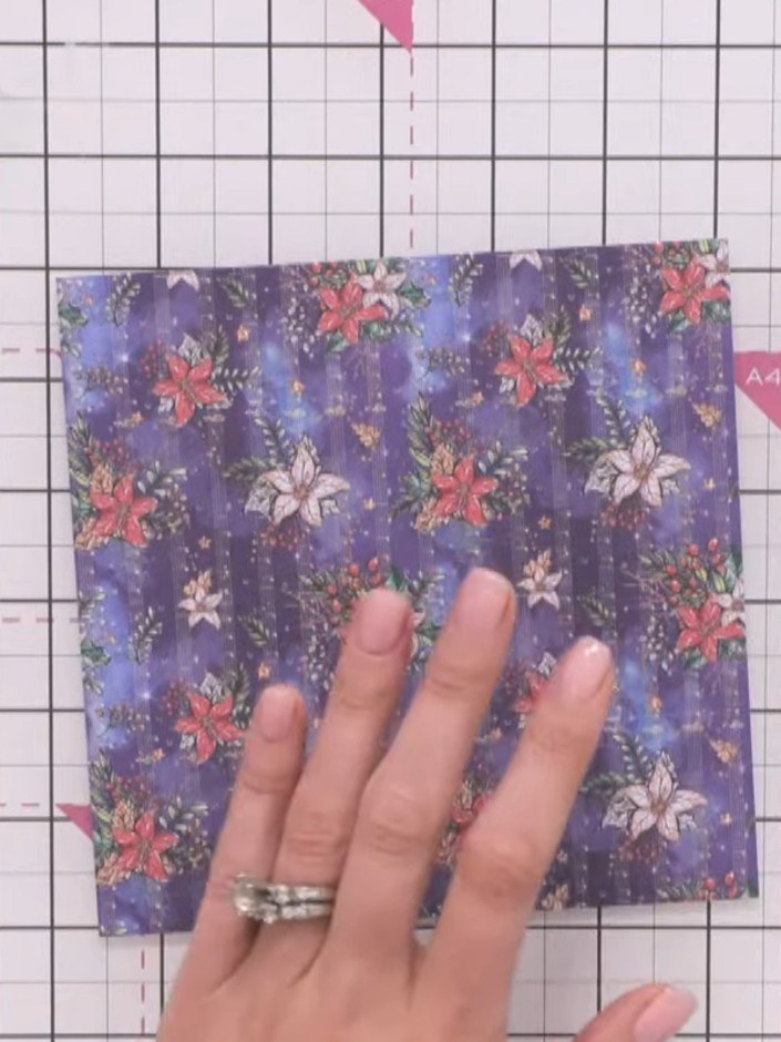 Step 6: Bring the bottom point of the purple floral paper up to meet the top point, creating a triangle. Burnish the f
