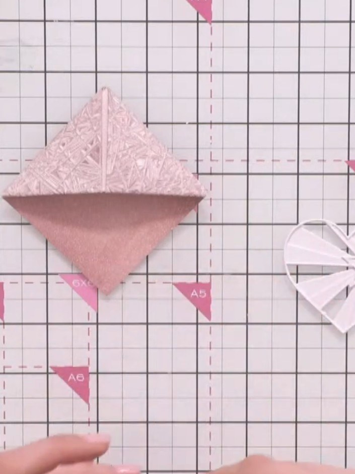 Step 11: Glue the layered heart decoration to the corner point of your folded bookmark, aligning the point of the heart