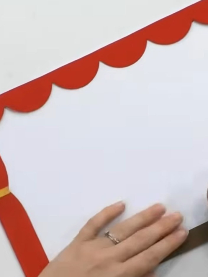 Step 2: Attach the decorative frame pieces around all four sides of the white card base. Position the red scalloped st
