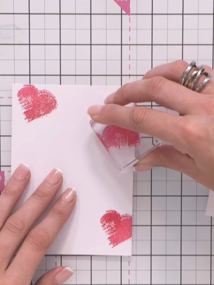 Step 2: Ink the textured heart stamp in pink. Stamp it three times across the card front, positioning some hearts part