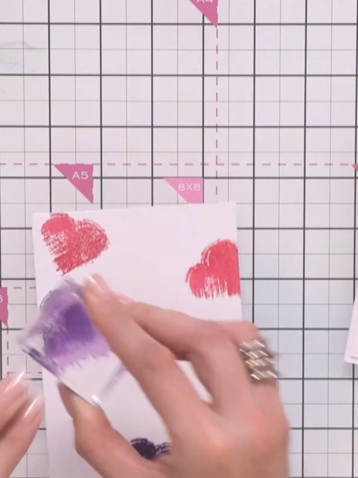 Step 3: Clean the stamp and ink it in purple. Stamp three more hearts in different areas of the card to create a varie