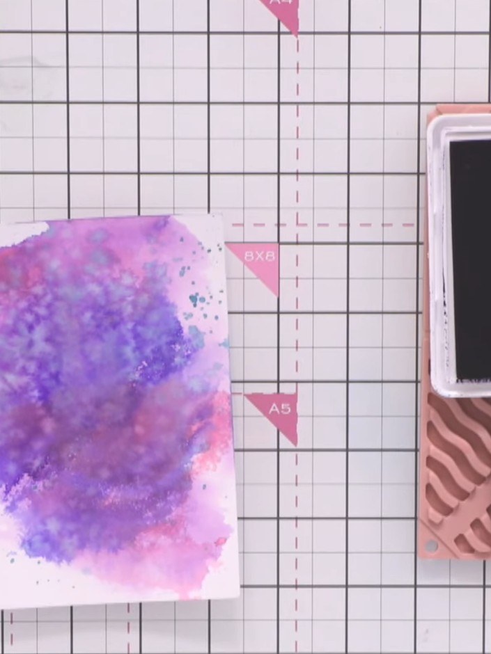Step 1: Gather your purple and pink watercolour background card along with black and indigo ink pads. You'll also need