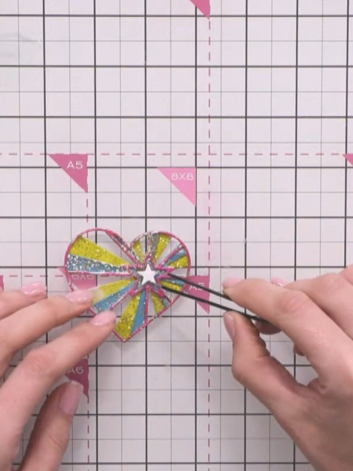 Step 14: Glue a smaller die-cut heart to the centre of the layered heart stack using adhesive. Position it carefully to