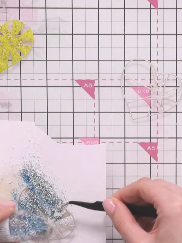 Step 9: Sprinkle blue embossing powder with gold flecks over the second heart. Heat-set the embossing powder with a he