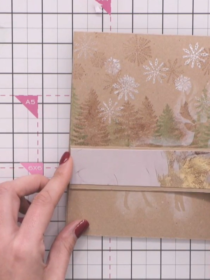 Step 13: Adhere the banner strip horizontally across the card front, positioning it so the stag remains visible behind 
