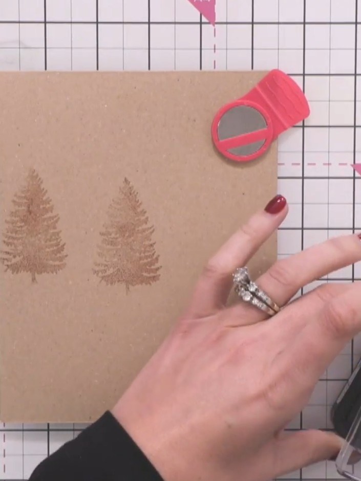 Step 3: Stamp additional tree images in varying sizes and positions across the kraft card to create depth and a sense 