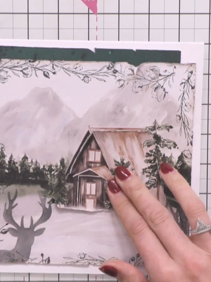 Step 10: Position the layered winter cabin scene onto the white card base, adjusting it slightly to ensure it sits cent
