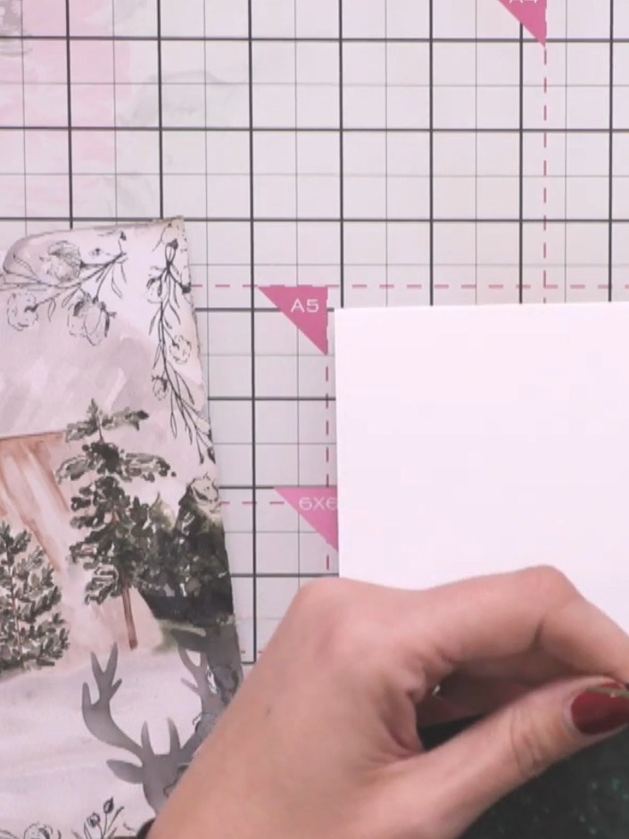 Step 9: Attach the dark green glittery cabin panel to the corner of the white card base using foam tape. Distress the 