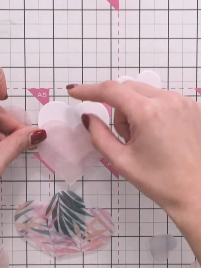 Step 2: Falte Transparentpapier in der Mitte und stanze große Hutformen durch beide Lagen – so bekommst du mit einem einzigen Stanzvorgang gleich zwei Teile.